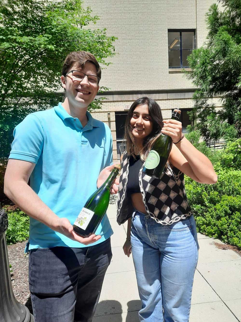Elya and John holding bottles of Champagne
